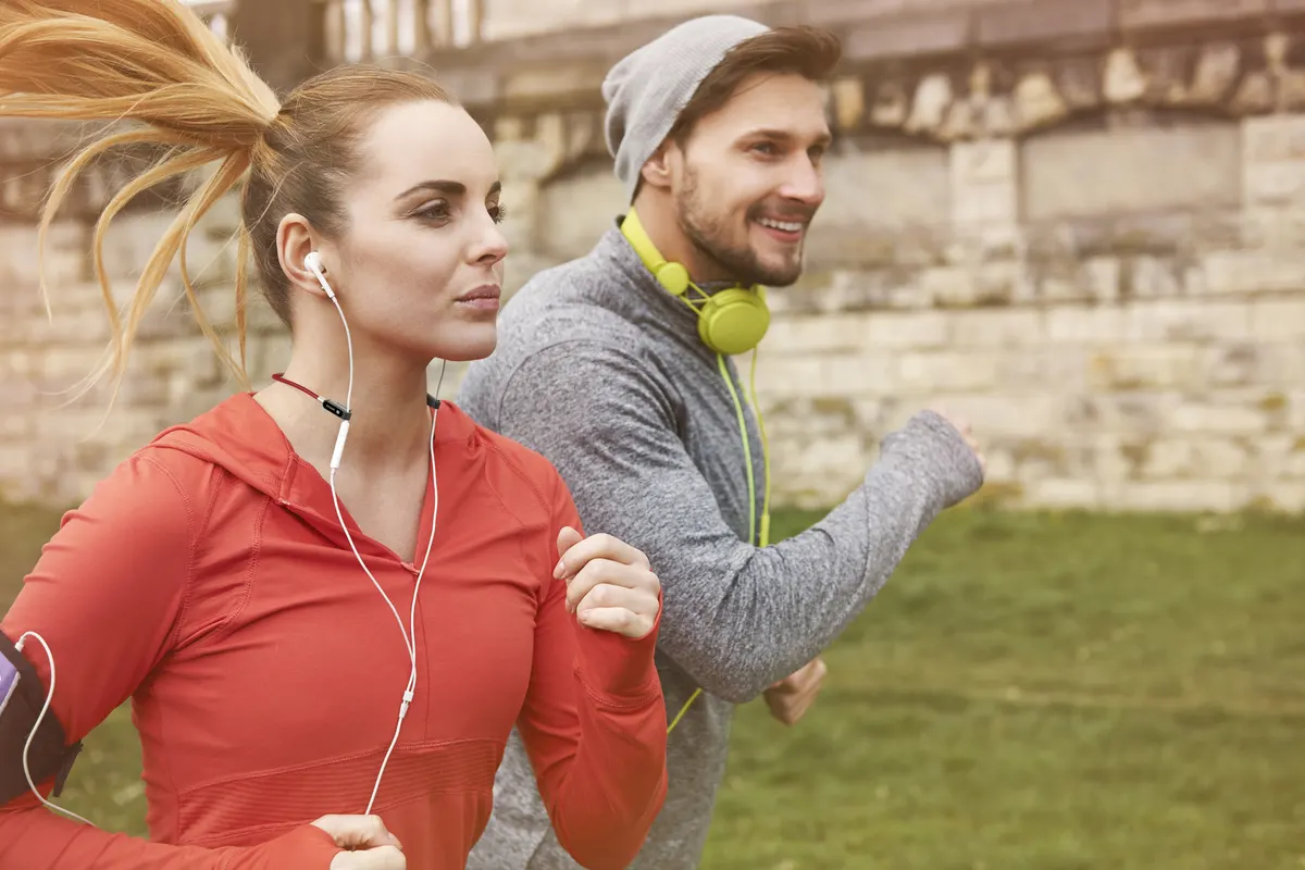 Joggeuse écoutant de la musique, cordon SPARK rouge maintenant ses écouteurs pendant l'effort.